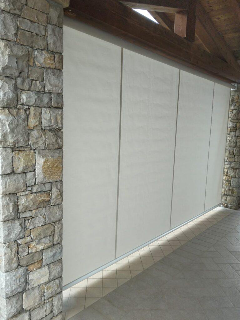 Parete di pietra con tende bianche.